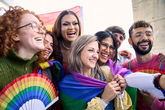 Group of happy diverse young friends taking a selfie photo enjoying together on gay pride day. Joyful LGBT community people gathered hugging and smiling outdoors. Relationships of generation z