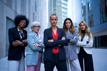Portrait of multiracial and diverse ages business women in formal suits posing serious with arms crossed looking at camera. Empowered and successful female entrepreneurs happy and powerful outdoor - obrazy, fototapety, plakaty