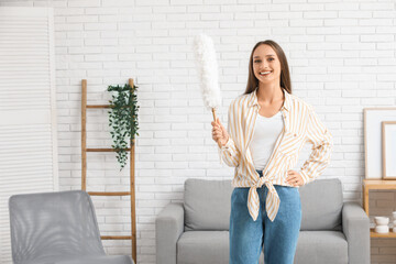 Pretty young woman with pp-duster in living room
