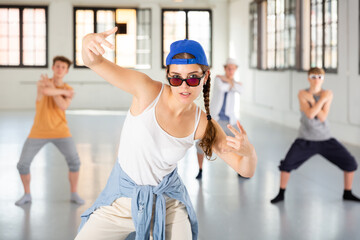 Teenage girl practicing hip hop moves with friends at group dance class