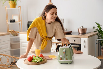 Young beautiful happy woman making tasty toasts in kitchen