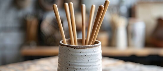 Wooden crochet hooks placed inside an attractive handmade ceramic mug in the setting of a knitting studio.