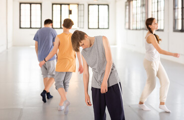 Portrait of teenage boy dancer having group contemporary dance training at dance hall