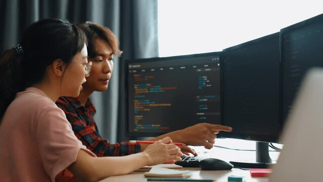 Slow motion back end software developer engineer for computer programming working together on debugging writing computing code, solving complex algorithms display on monitor in office. Burgeoning