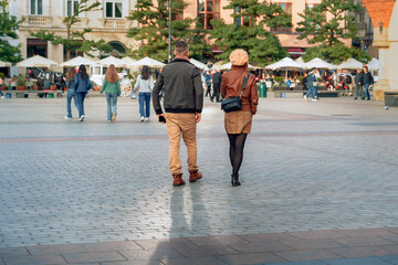 Young couple in a busy city square in the evening showing the 2024 urban exploration trend, perfect...