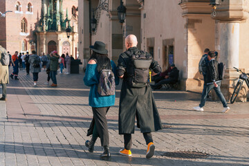 Exploring the city in 2024: A bald man in a coat and a woman in a hat with backpacks walk together...
