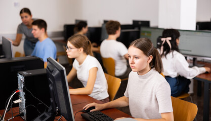 Fototapeta premium Girl preparing for exam in college library, using pc for searching information