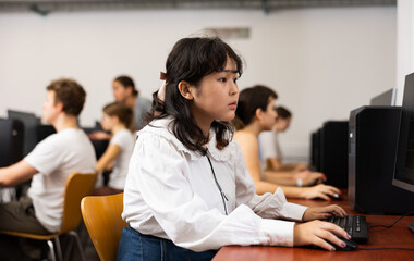 Teen schoolgirl learning basics of programming in group course in computer college