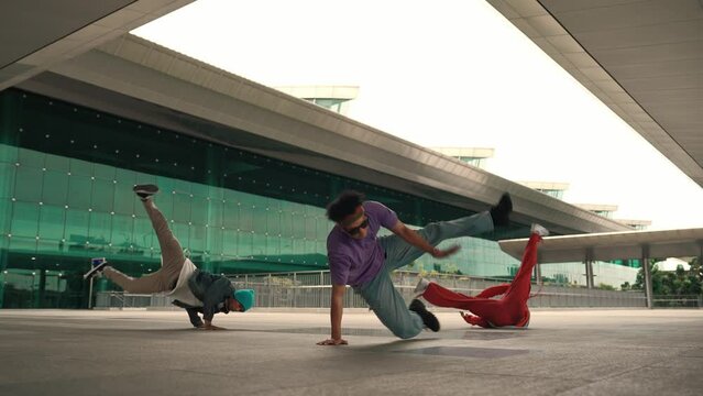 Group of diverse hipster or street dancer doing head spin in front of mall. Happy energetic break dancer practice b-boy step dancing with friends. Outdoor sport 2024. Street dancer concept. Sprightly.