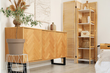 Interior of stylish bedroom with paintings, commode and shelf unit