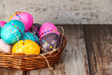 Easter eggs in a brown vintage basket on a wooden table