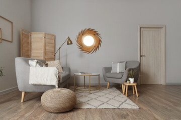 Interior of living room with golden mirror, sofa and armchair