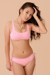 Fototapeta premium Attractive young woman in swimsuit on beige background