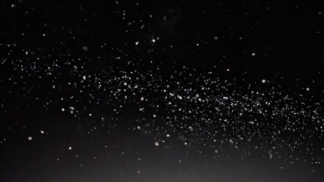 Snow dust against black background. Slow motion of white glittering particles