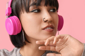 Stylish young woman in headphones with nose piercing on pink background, closeup - obrazy, fototapety, plakaty