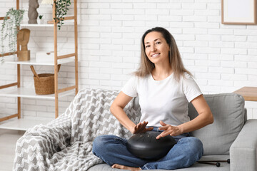 Happy mature woman with glucophone on sofa at home