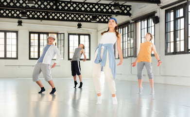 Fototapeta premium Teenager girl and boys exercising hip-hop dancing indoors