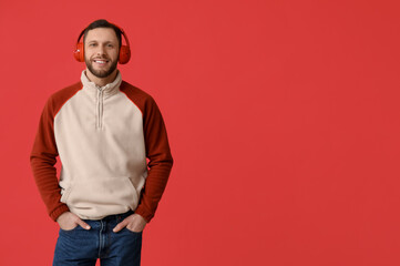 Young man in modern headphones on red background