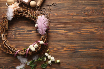 Supplies for creating Easter wreath with feathers and flowers on brown wooden background