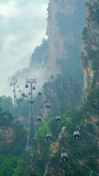 Famous tourist attraction of China - Zhangjiajie stone pillars cliff mountains in fog clouds with cable railway car lift at Wulingyuan, Hunan, China