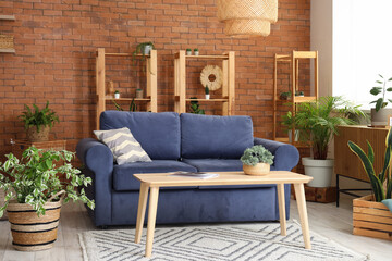 Interior of loft style living room with sofa, shelving units, table and houseplants