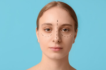 Young woman with marks on her face against blue background. Blepharoplasty concept