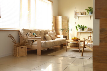 Interior of light living room with wind chime, sofa and table