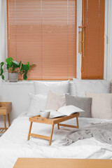 Interior of light bedroom with wind chime and stand on bed