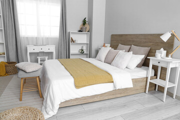 Interior of light modern bedroom with big bed, window, shelving units and bedside table