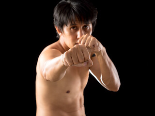 With intense focus and readiness for training, a young Asian martial artist strikes a punching...