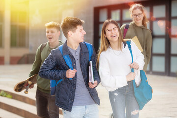 Cheerful teenage boys and girls walking together after lessons