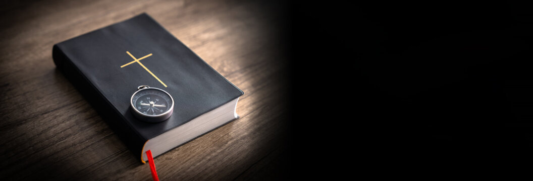 Bible on wooden table, compass on it, word of God as guidance concept