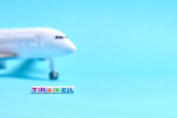 Passenger plane on a blue background with the inscription travel next to it. Travel concept