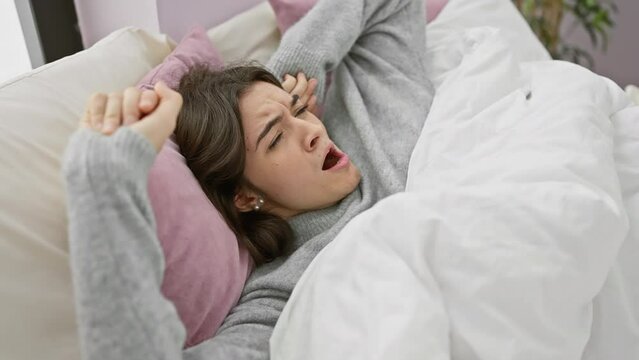 A young woman yawns while stretching in her bedroom, depicting a relatable morning scene in a cozy indoor setting.