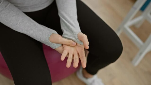 Young woman in a therapy session showing her hand with an exercise ball at the rehab clinic.