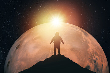 Silhouette of an astronaut on top of a mountain against the background of Mars. Elements of this image furnished by NASA