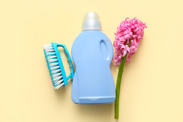 Bottle of detergent, brush and beautiful hyacinth flower on beige background