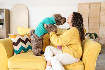 Young woman with cute poodle sitting on sofa at home