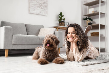 Young woman with funny poodle lying on floor at home