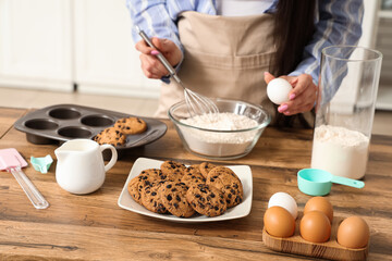 Beautiful young woman preparing dough for tasty cookies with chocolate chips in kitchen, closeup