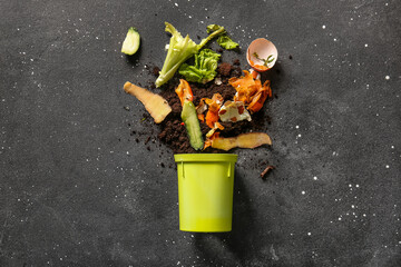 Bin with organic waste and soil on grey grunge background. Compost recycling concept