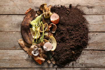 Organic waste and soil on wooden background. Compost recycling concept