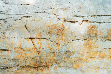 Closeup of a cracked stone wall with a beige brick pattern