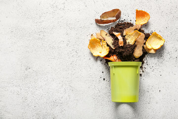 Bin with organic waste and soil on white grunge background. Compost recycling concept