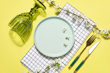 Beautiful table setting with blossoming branches on yellow background