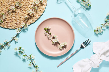 Beautiful table setting with blossoming branches on blue background