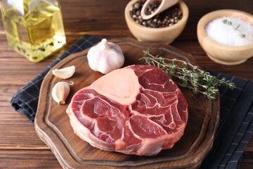 Piece of raw beef meat, garlic and thyme on wooden table, closeup