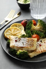 Tasty cod cooked with vegetables served on grey table, closeup