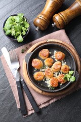 Delicious fried scallops in dish served on dark gray textured table, flat lay