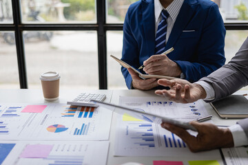 Two business partner colleagues discuss financial and company planning graph during budget meeting....